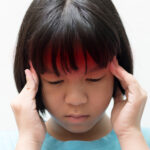 A child holding her head after a brain injury in Atlanta